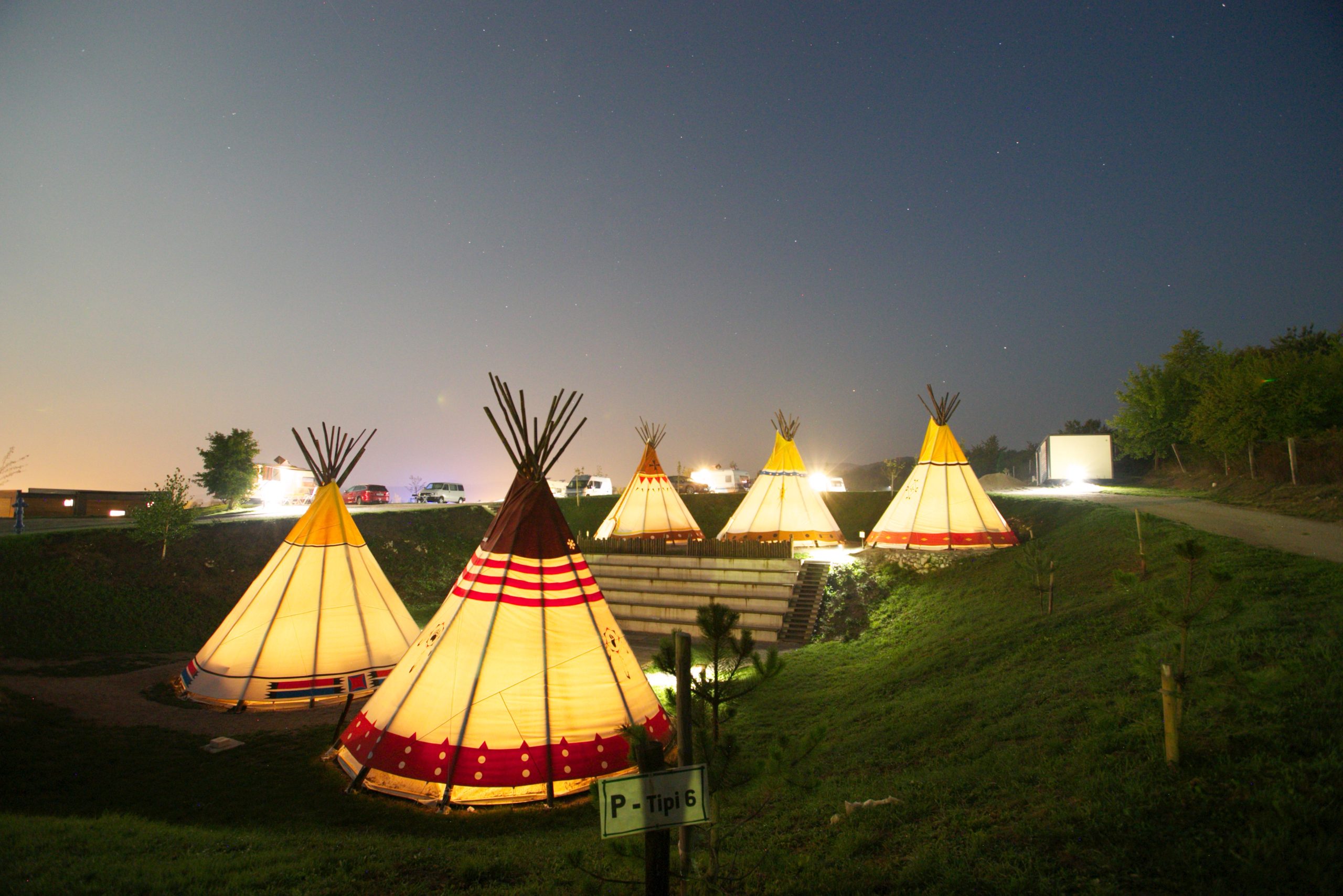 Tipi tents glowing at sunset in a green valley at Plitvice Holiday Resort